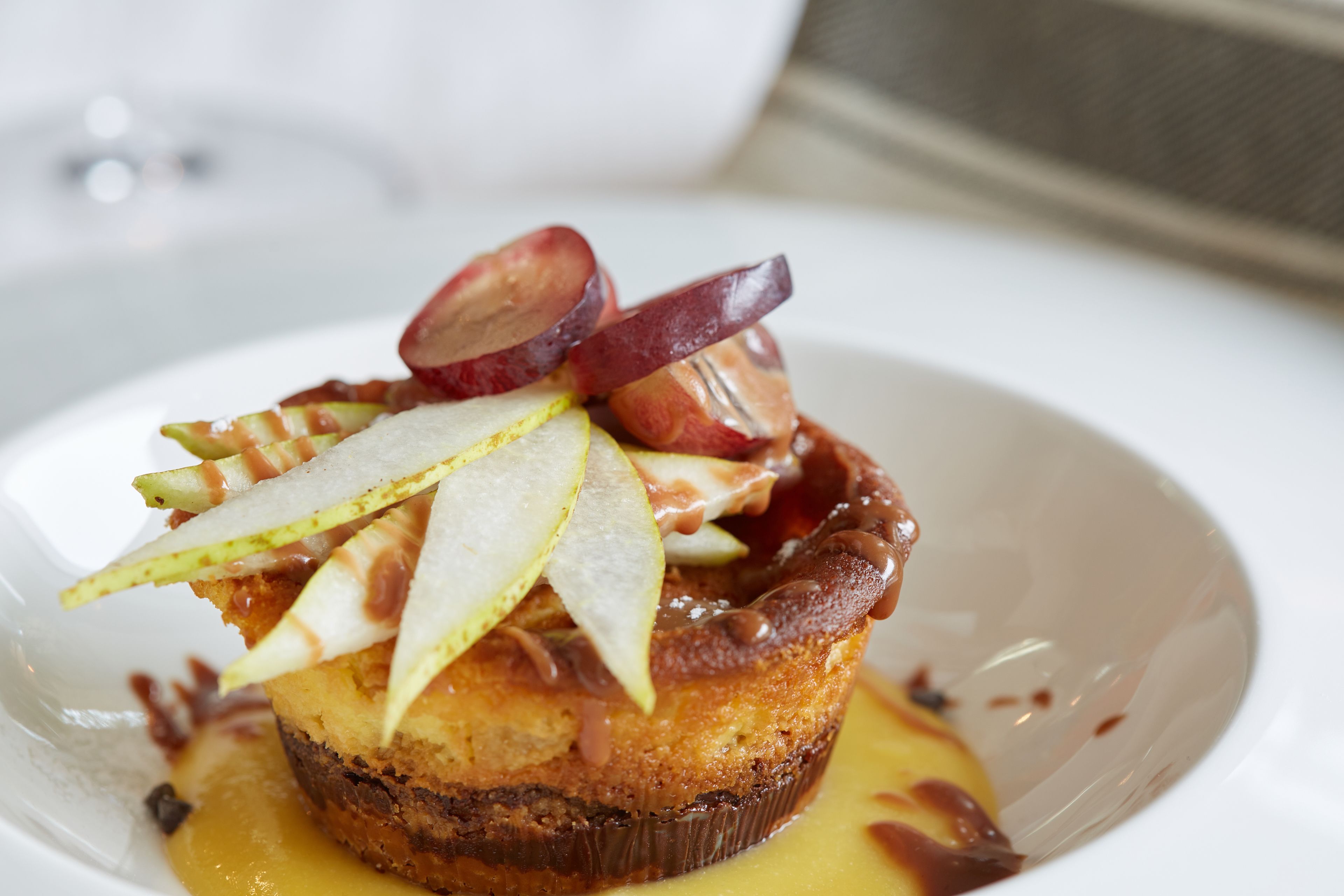 A dessert with fruit and sauce on a white plate.