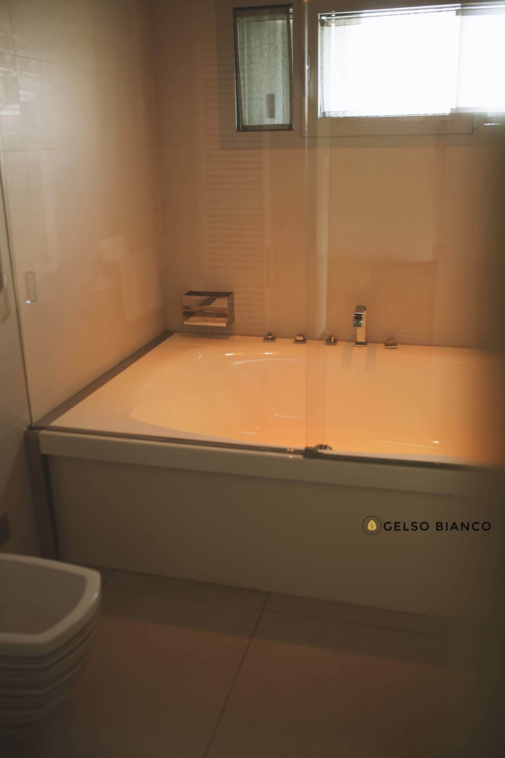 A bathroom with a bathtub, a window, and a toilet.