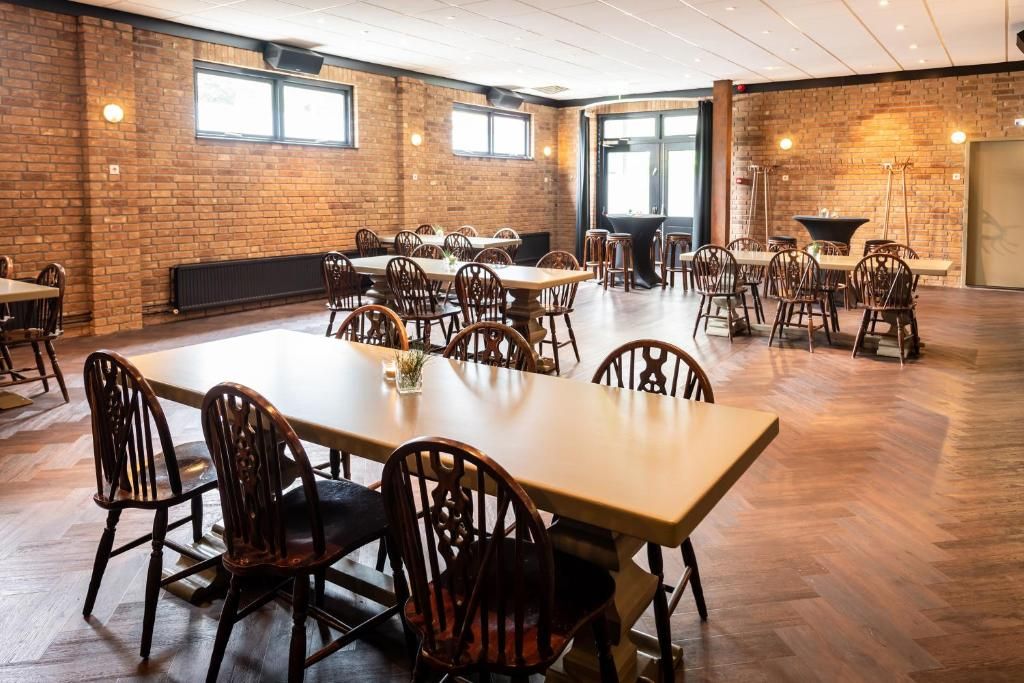 A spacious dining area with brick walls, multiple tables and chairs, and large windows allowing natural light.