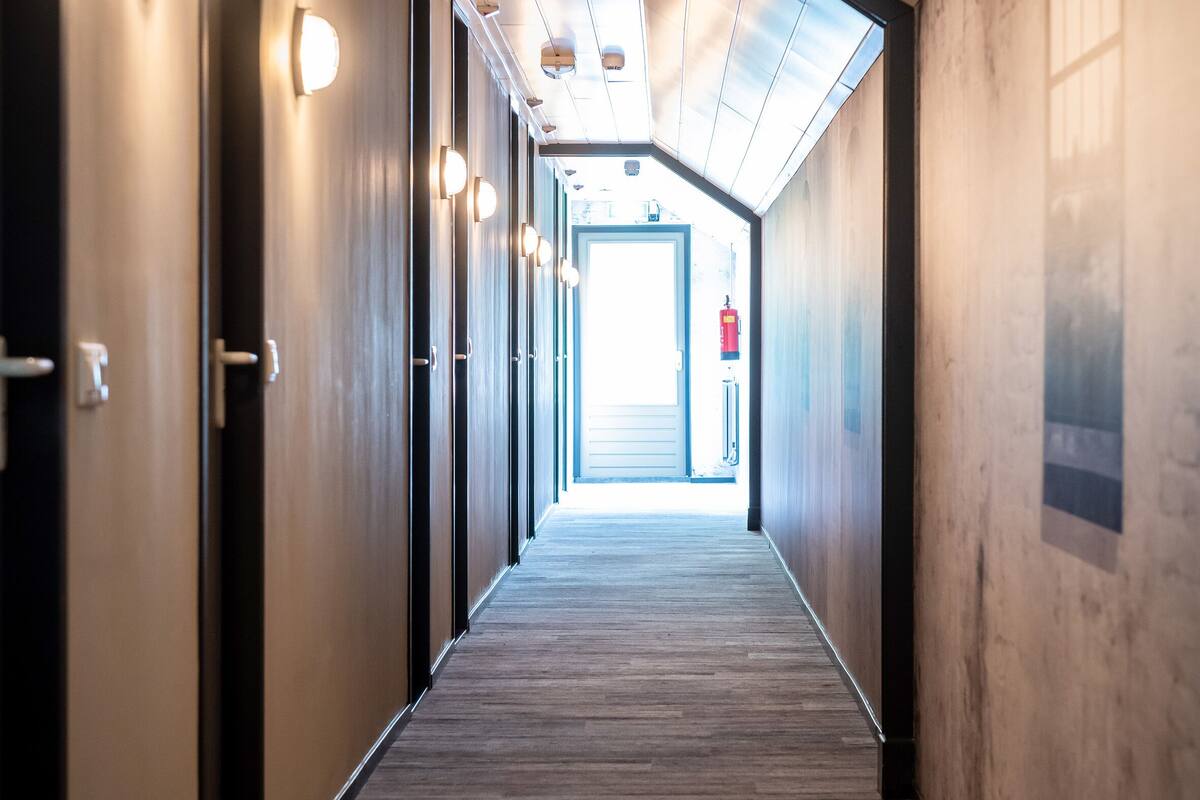 Corredor com piso de madeira, iluminação embutida e portas em ambos os lados.
