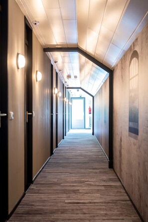 A hallway with wooden flooring, recessed lighting, and doors on both sides. - De Drie Linden (Luyksgestel)