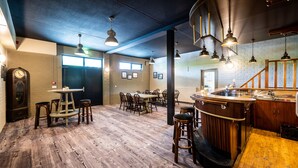 A restaurant with wooden flooring, bar area, and multiple tables and chairs.