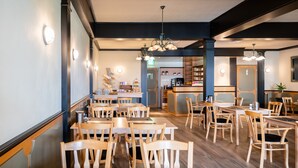 A restaurant with wooden tables and chairs, a bar area, and a counter with various items.