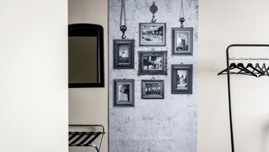 A room with a wall-mounted picture frame gallery, a metal coat rack, and a foldable chair.
