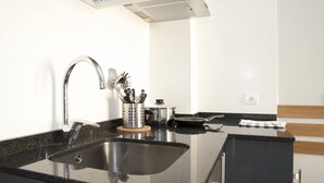 A modern kitchen with a stainless steel sink, a range hood, and a wooden countertop. - Apartamentos Sabinas Don Jaime (Zaragoza)