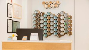 A reception desk with a wall art installation of tin cans, framed documents on the wall, and a wooden counter. - Apartamentos Sabinas Don Jaime (Zaragoza)