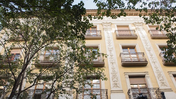 A multi-story building with balconies, ornate architectural details, and a tree in the foreground. - Apartamentos Sabinas Don Jaime (Zaragoza)