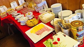 Een buffet met diverse gerechten en bestek, waaronder kommen, borden en een blik Cacao.