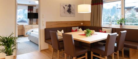 Un comedor moderno con una mesa de madera, sillas tapizadas en marrón y vistas a un paisaje nevado a través de amplios ventanales.