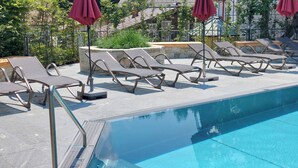 A poolside area with lounge chairs and umbrellas. - Appartement Schattauer (Wagrain)