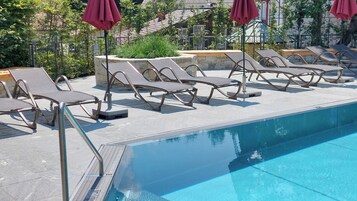 Una piscina al aire libre de temporada, sombrillas