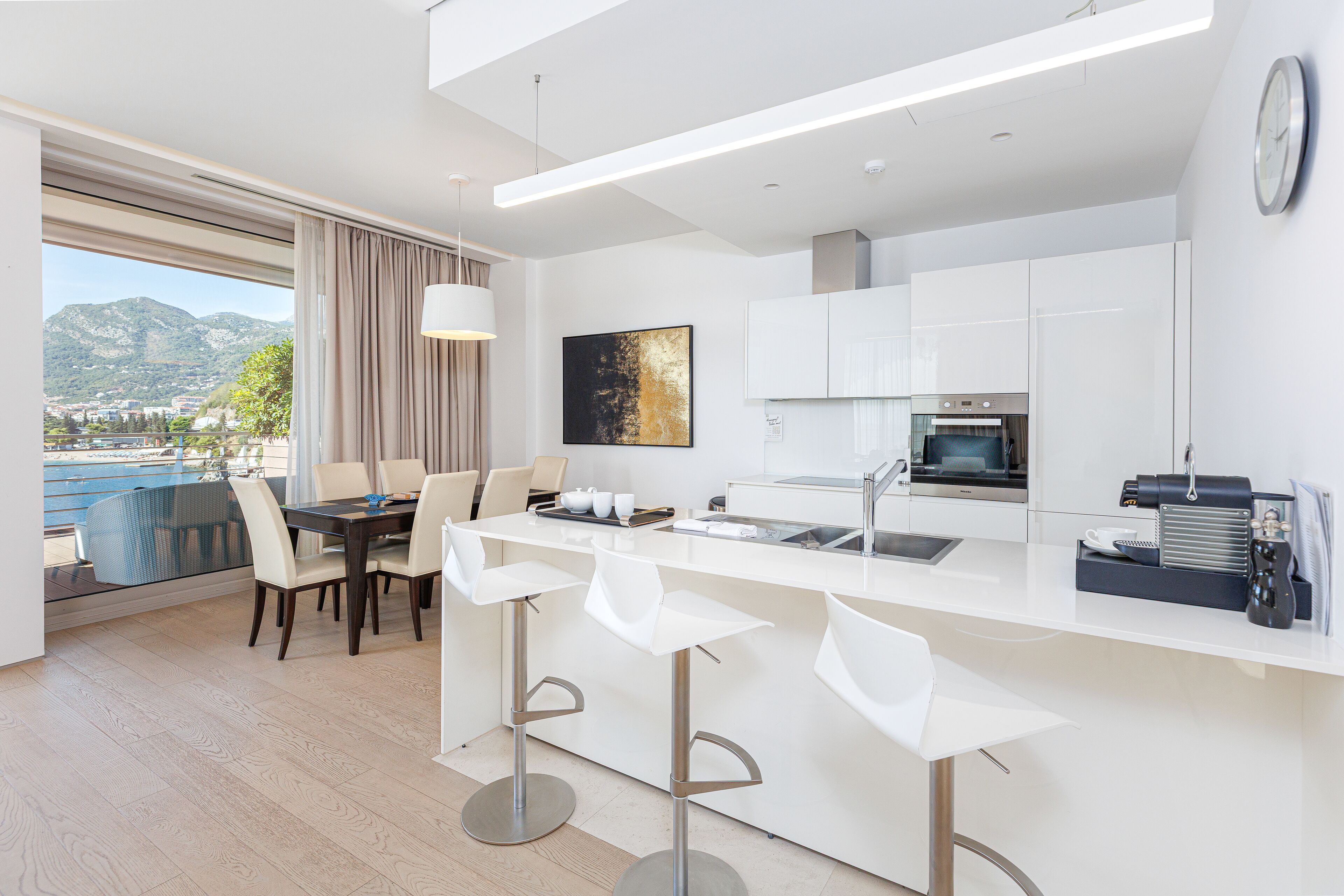 Una cocina moderna con una isla central, taburetes de bar y un comedor con vistas a las montañas.