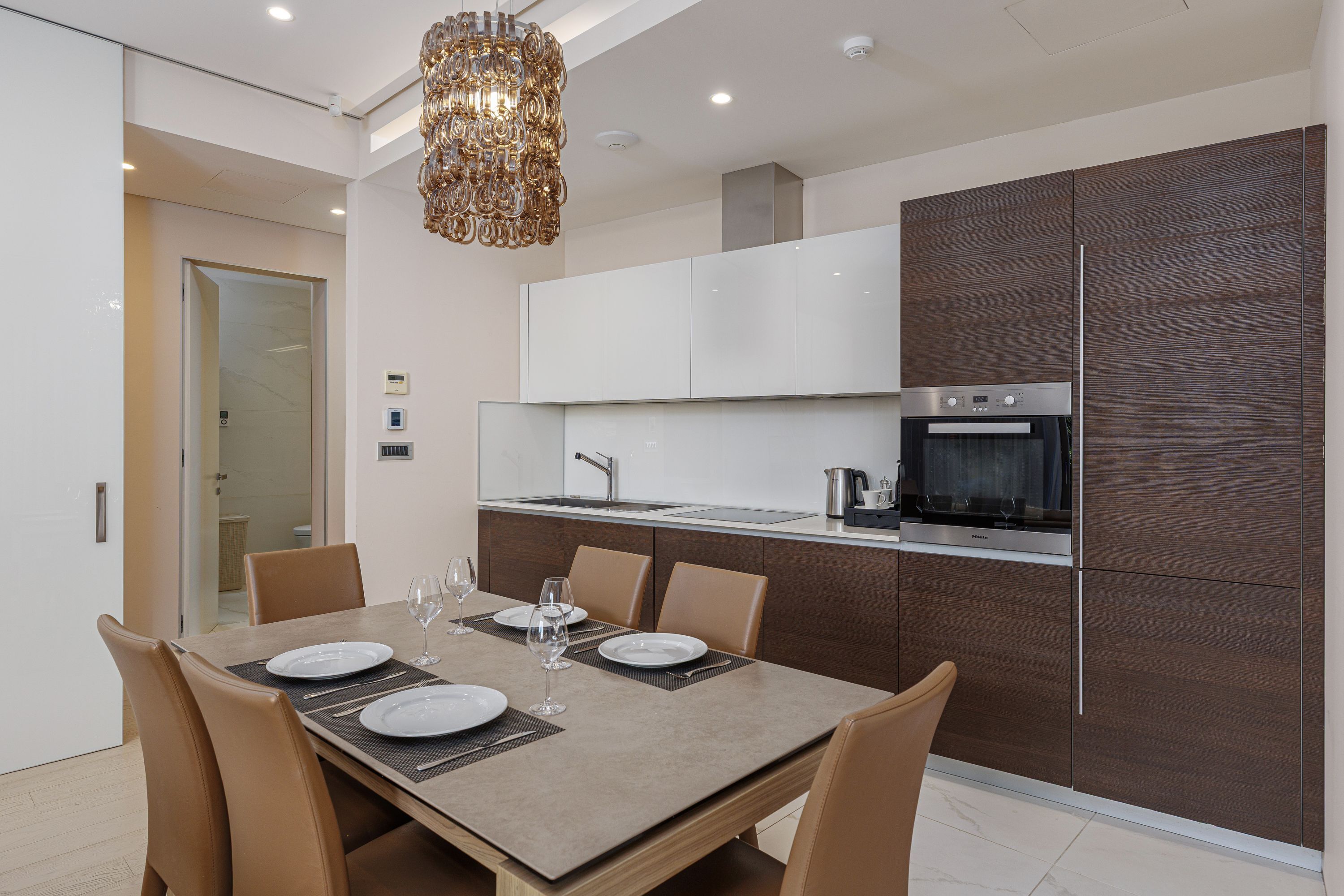 A modern kitchen with dark wood cabinets, a built-in oven, and a stainless steel refrigerator.