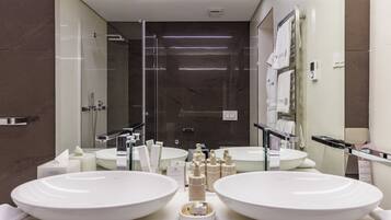 A modern bathroom with two large white sinks, a glass shower enclosure, and a mirror above the sinks.