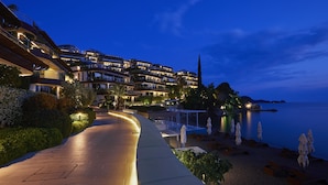 A coastal hotel with multiple balconies, a paved walkway, and beachside seating. - Dukley Hotel & Resort (Budva)