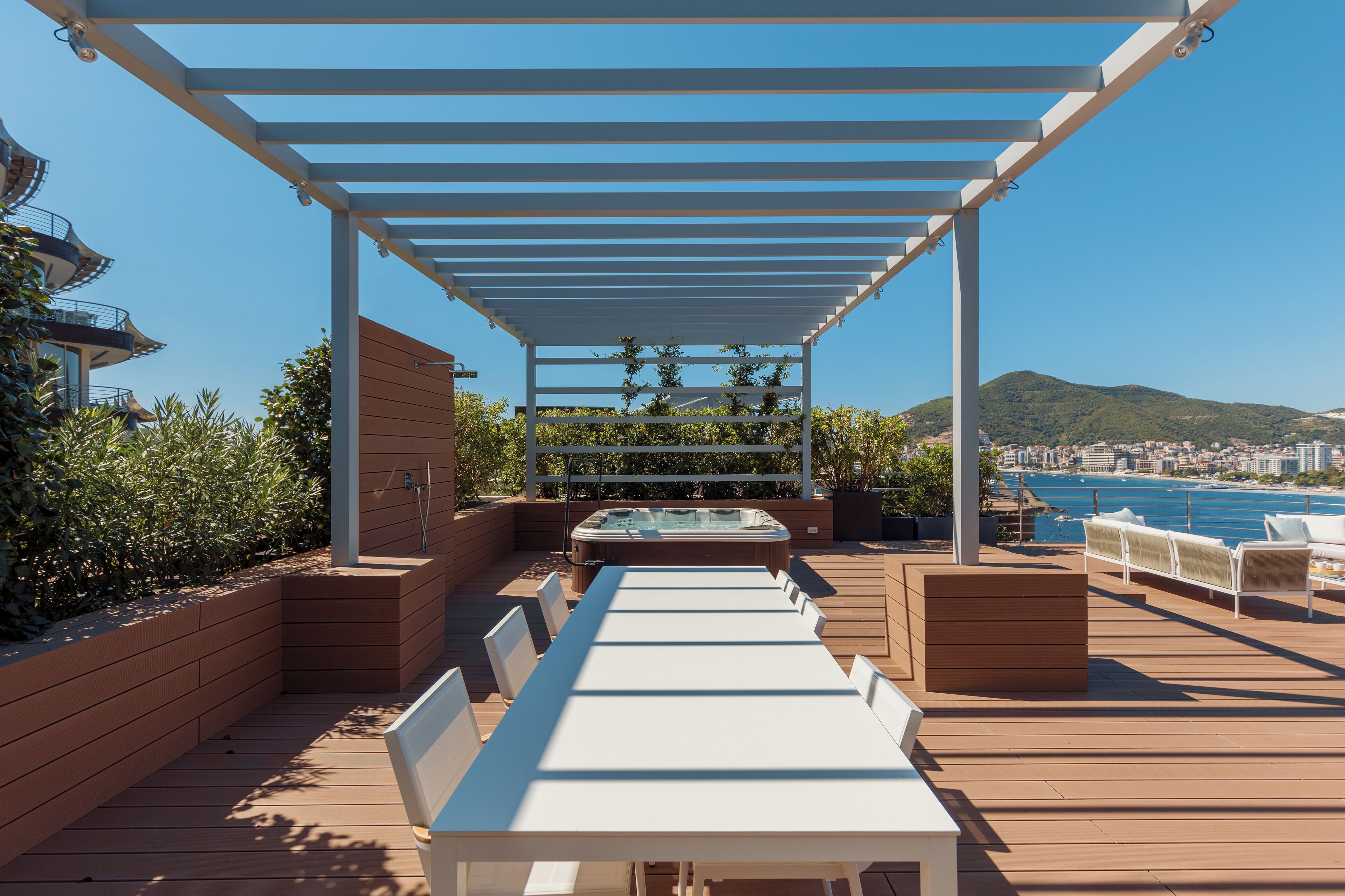 Eine Terrrasse im Freien mit Pergola, Sitzgelegenheiten und einem Whirlpool.