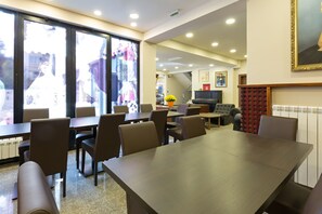 A modern dining area with a large table and chairs, a small coffee table, and a potted plant. - Sterling Hotel (Belgrade)
