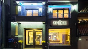 The exterior of the Sterling Hotel with a glass entrance, a reception desk, and a balcony with lights. - Sterling Hotel (Belgrade)