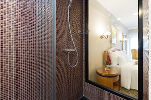A bathroom with a shower, a toilet, and a bed with white bedding. - Sterling Hotel (Belgrade)