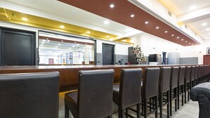 A bar area with a long counter, multiple bar stools, and a well-lit ceiling. - Sterling Hotel (Belgrade)