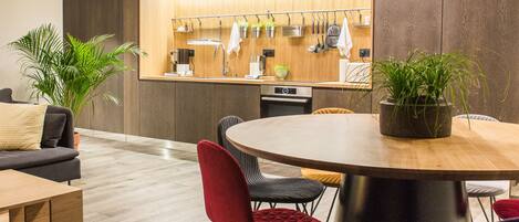 A modern kitchen with wooden cabinets, a built-in oven, and a hanging pot rack.