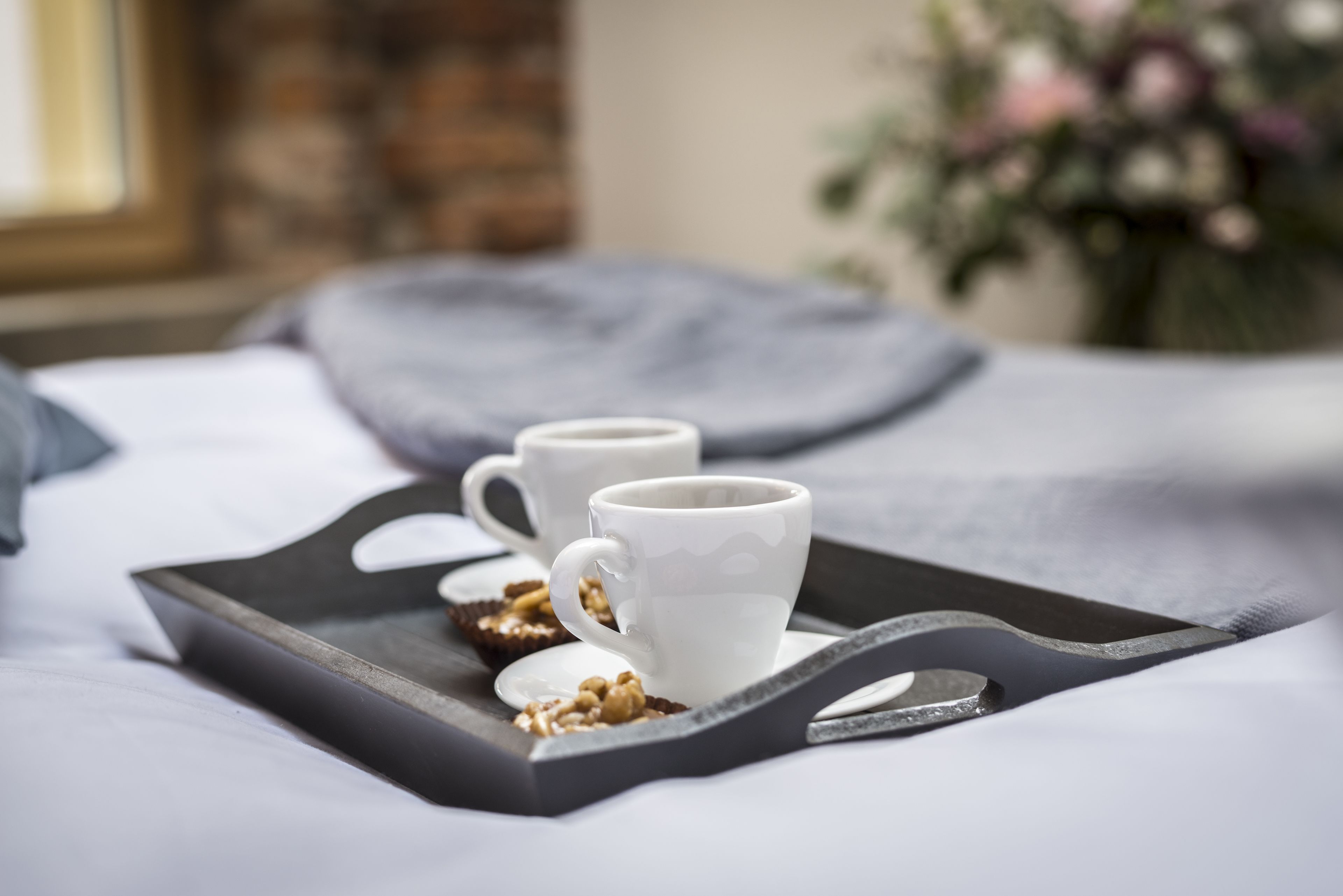 Un plateau avec deux tasses blanches et une petite assiette de noix.