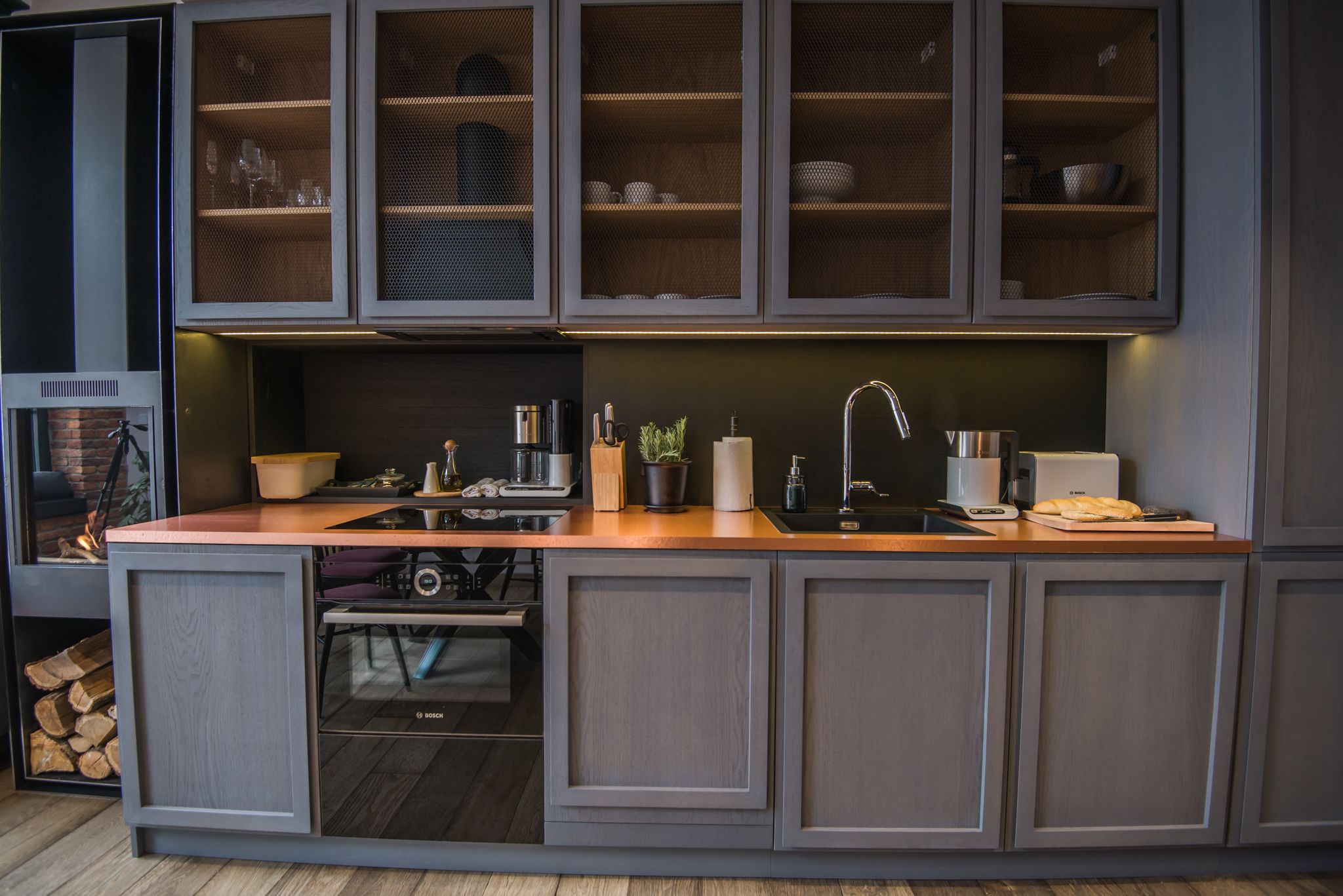 A modern kitchen with grey cabinetry, a wooden countertop, and a built-in sink.