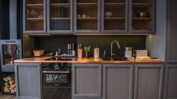 A modern kitchen with grey cabinetry, a wooden countertop, and a built-in sink.