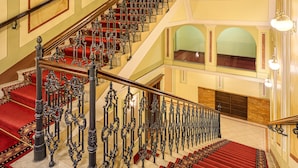 A grand staircase with ornate iron railings and red carpeted steps leading to an upper floor. - Hotel Bellevue Vienna (Vienna)