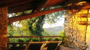 Una terraza con paredes de piedra, vigas de madera y dos sillas plegables.