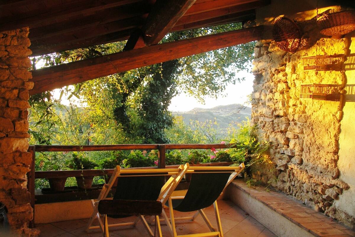 A terrace with stone walls, wooden beams, and two folding chairs.