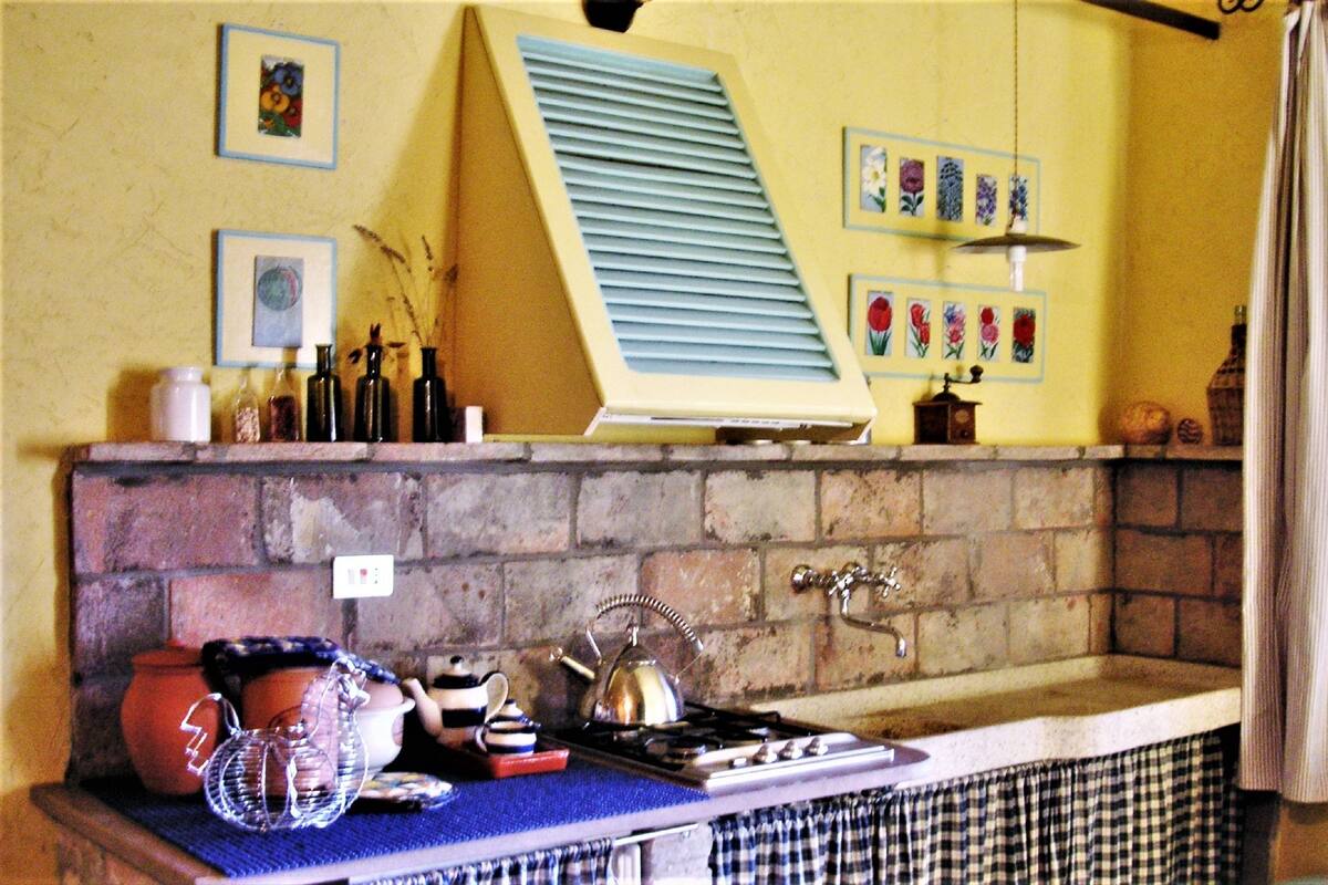 A kitchen with a brick backsplash, a gas stove, and various kitchen items.
