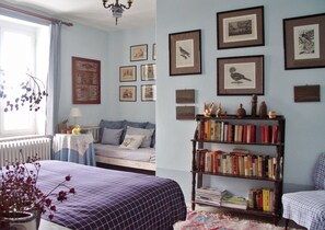 A bedroom with a bed, a bookshelf, and framed pictures on the wall.