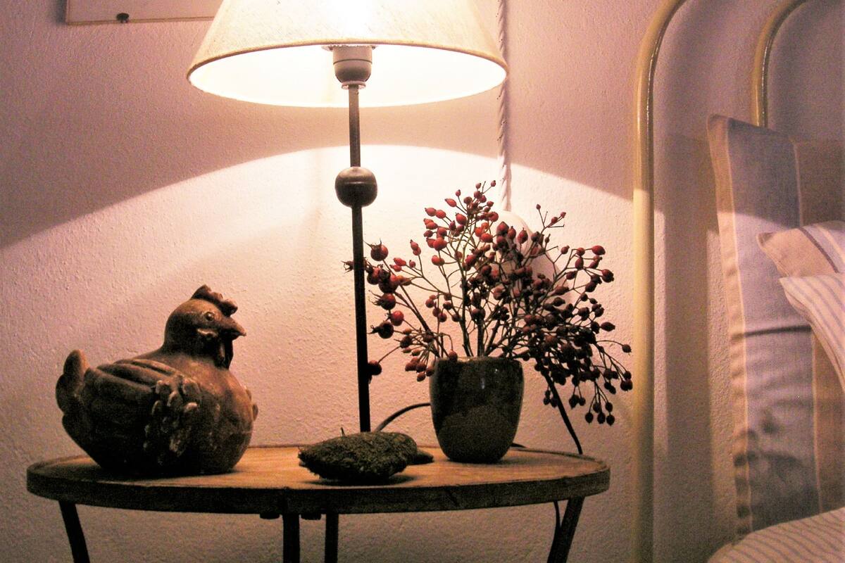 A table with a lamp, a potted plant, and a small figurine.