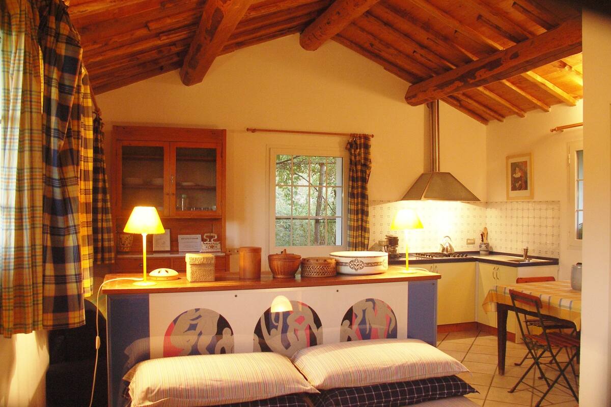 A cozy room with a bed, a small table, a kitchen area, and a window.