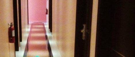 A long, narrow hallway with a reflective floor and doors on both sides.
