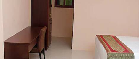 A bedroom with a bed, a desk, and a chair.