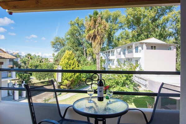 A balcony with a table, two chairs, a bottle of wine, and two wine glasses. - Cavos Beach House (Corfu)