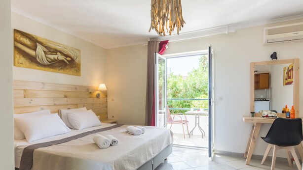 A hotel room with a bed, a desk, a chair, a balcony, and a painting on the wall. - Cavos Beach House (Corfu)