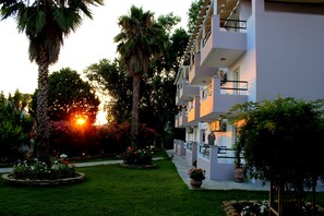 A hotel with a garden, palm trees, and a sunset. - Cavos Beach House (Corfu)