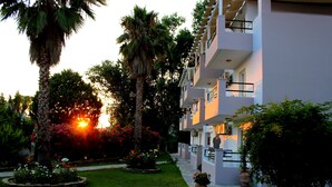 A hotel with a garden, palm trees, and a sunset. - Cavos Beach House (Corfu)