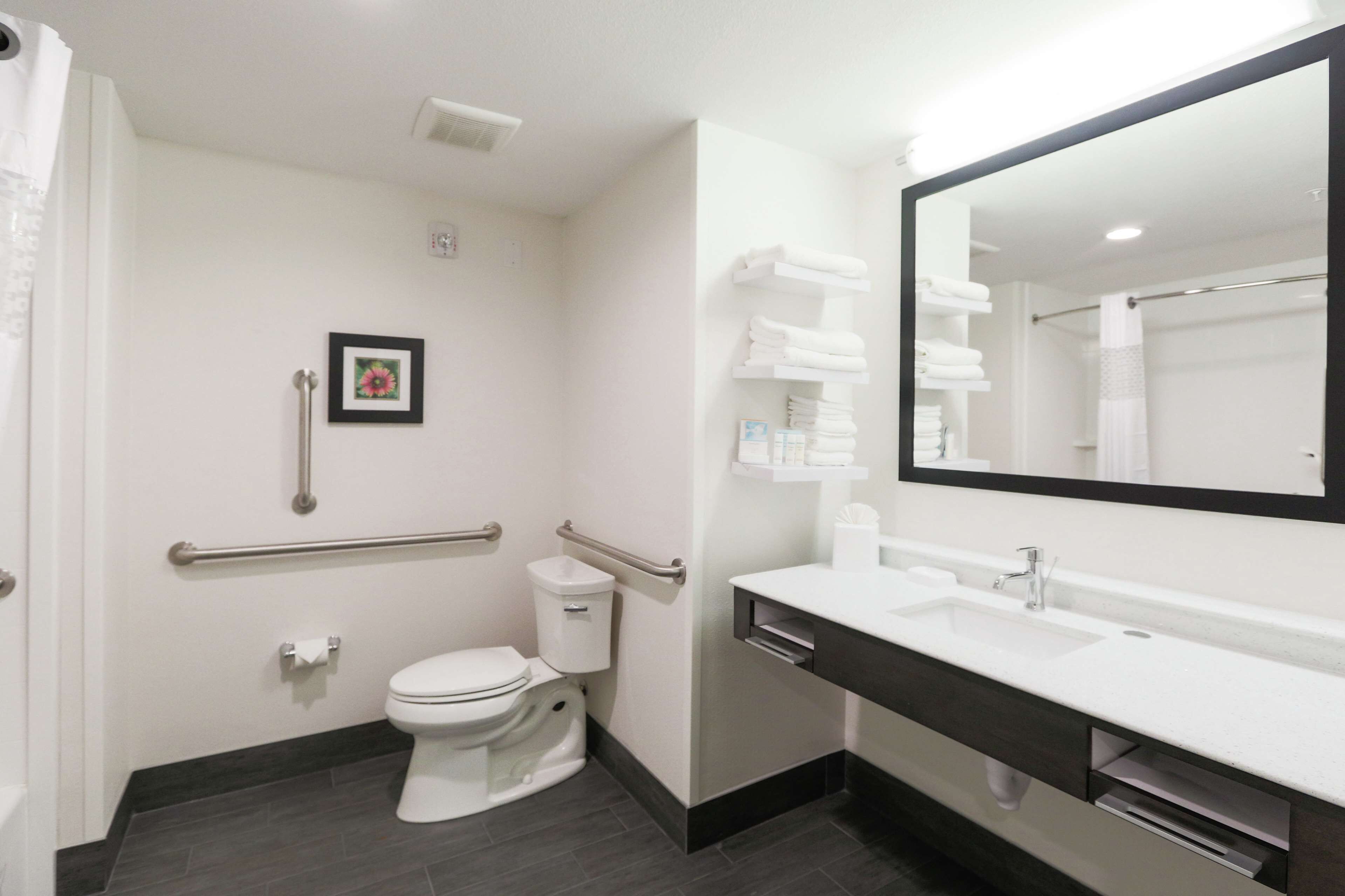 Un baño moderno con inodoro blanco, lavamanos y un espejo grande.