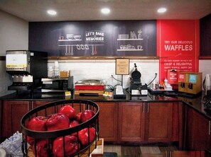 A kitchen area with a counter, a coffee machine, a microwave, and a sign that says "HAPPY BREAKFAST STARTS HERE".