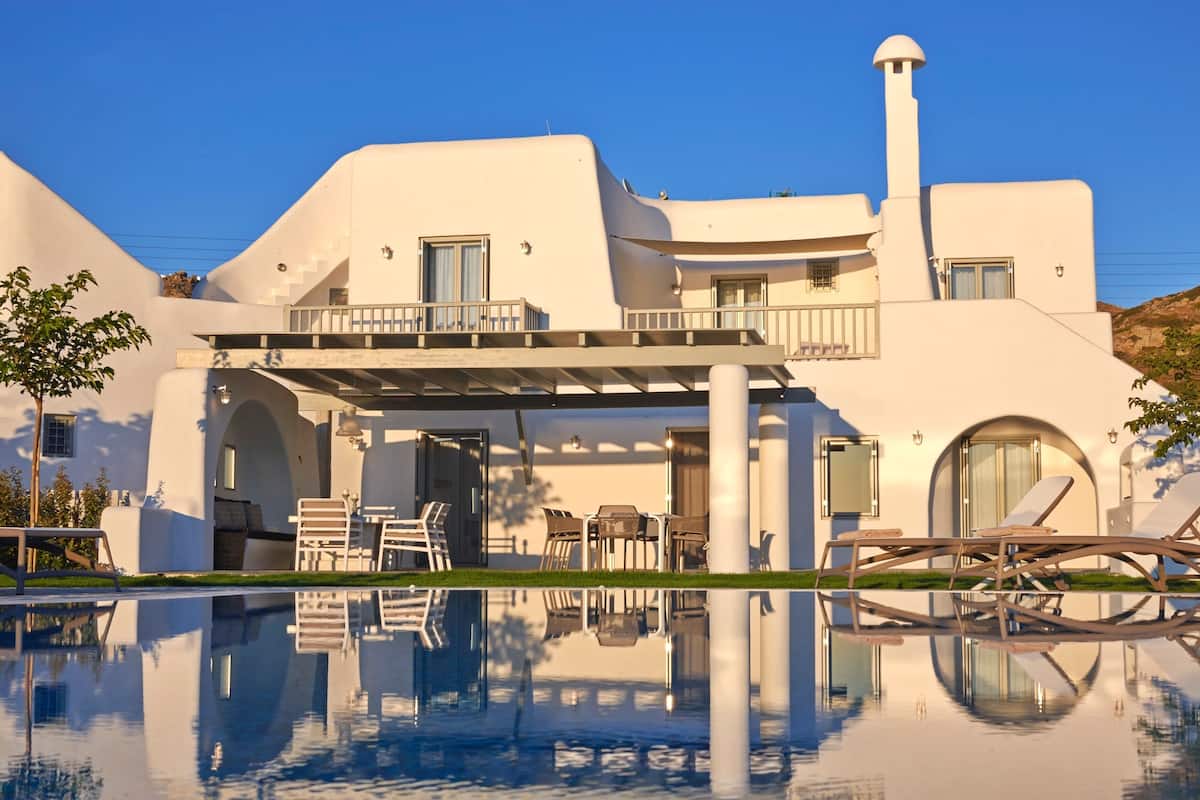 Ein modernes, weißes Gebäude mit Pool, Außenbereich mit Sitzgelegenheiten und einer überdachten Terrasse.