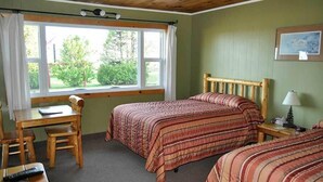 Una habitación con dos camas, un escritorio de madera, una silla, una lámpara y una ventana con cortinas.