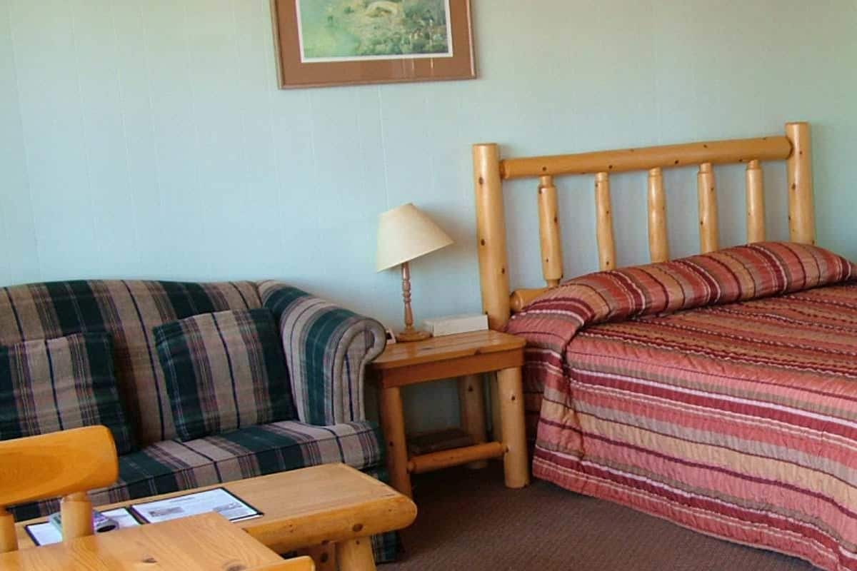 Een kleine, gezellige kamer met een enkel bed, een slaapbank, een tafel en een televisie.