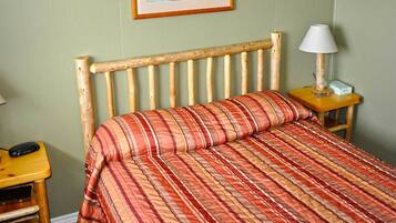 Una cama con una manta a rayas, un cabecero de madera y dos mesitas de noche con lámparas.