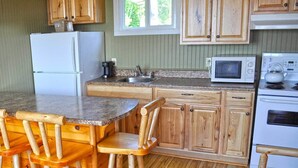 Una cocina con armarios de madera, un refrigerador, un microondas, una estufa y una encimera de granito.