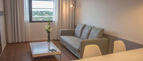 A modern living room with a sofa, a coffee table, and a dining table.