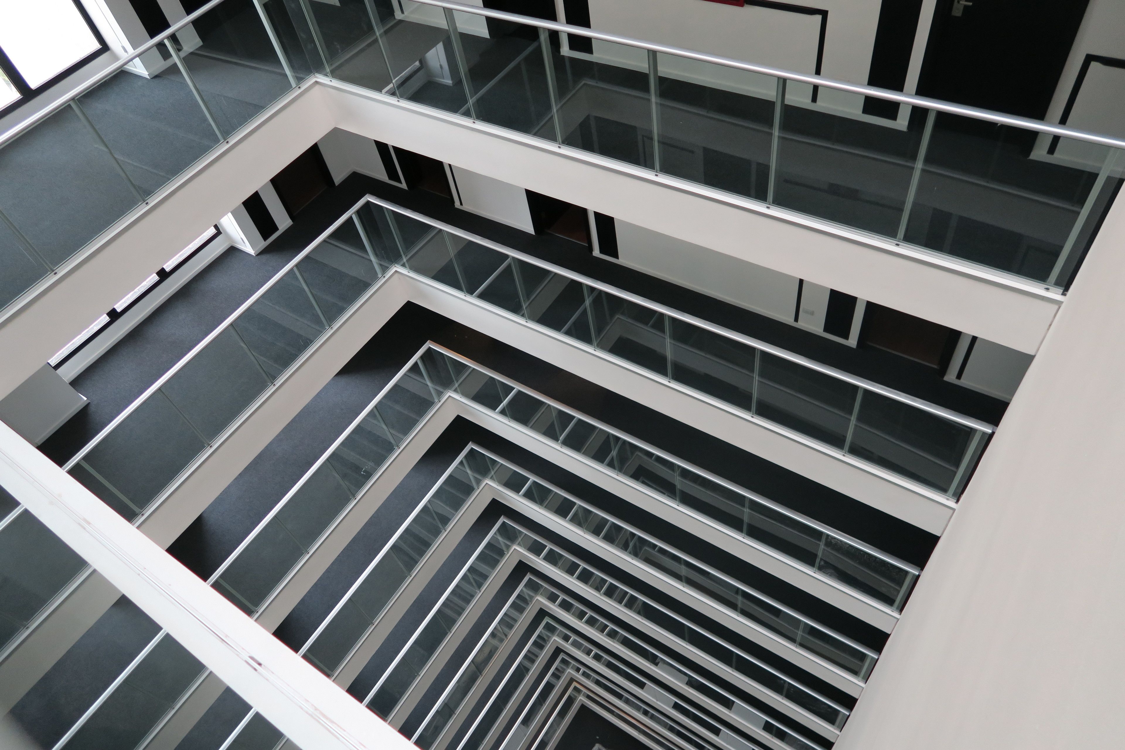 Un intérieur moderne avec un escalier aux murs de verre menant à plusieurs étages.